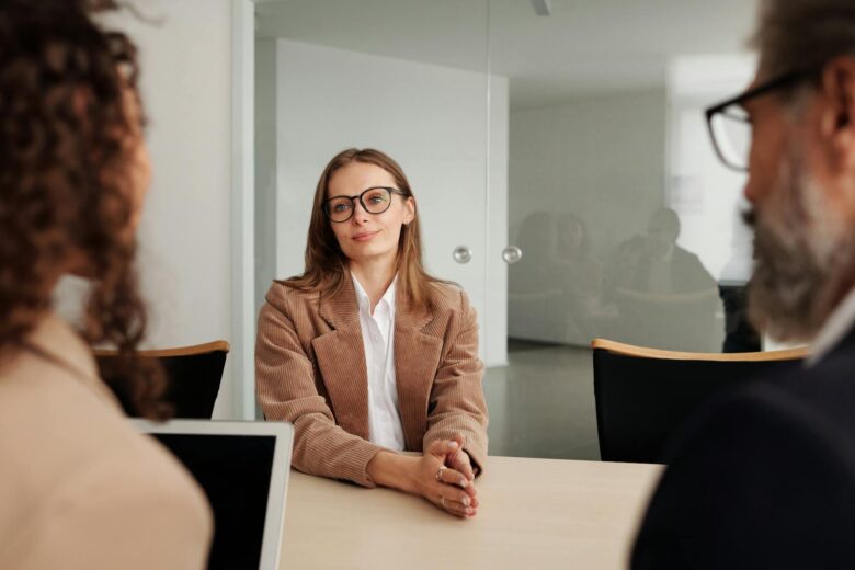 Woman in Brown Blazer seated beside Table